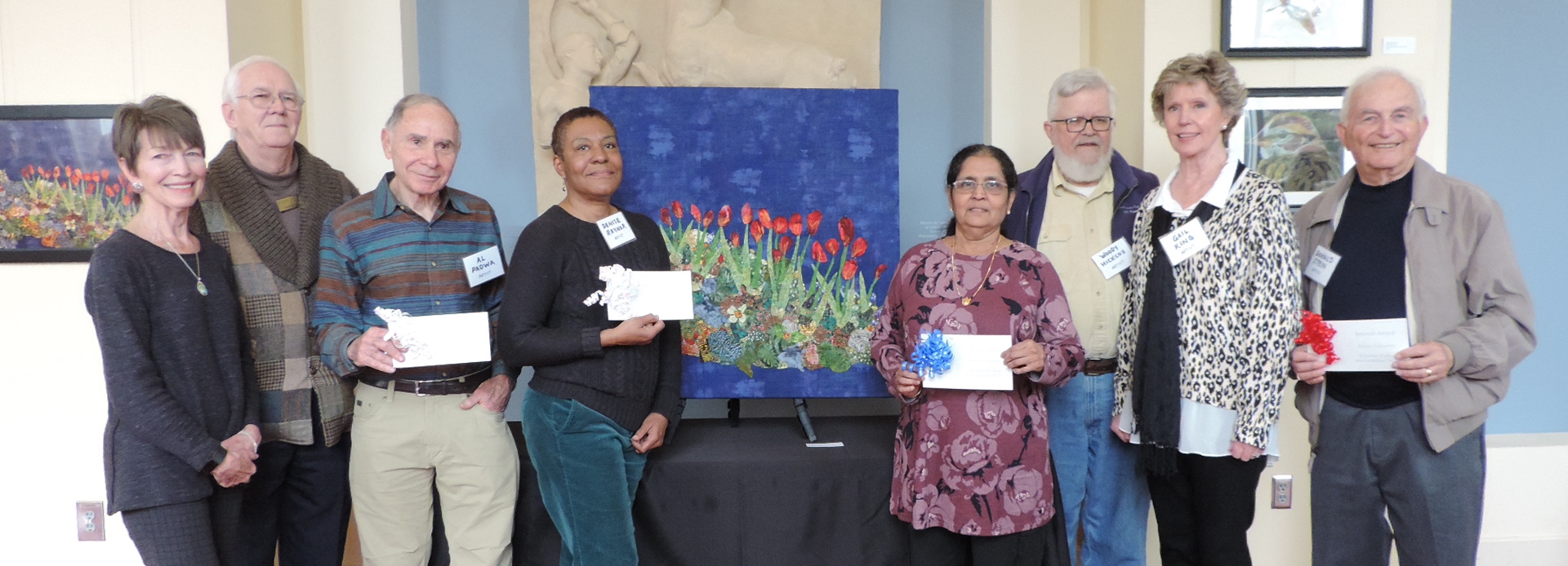 Group of people holding standing in front of art at the Art Show